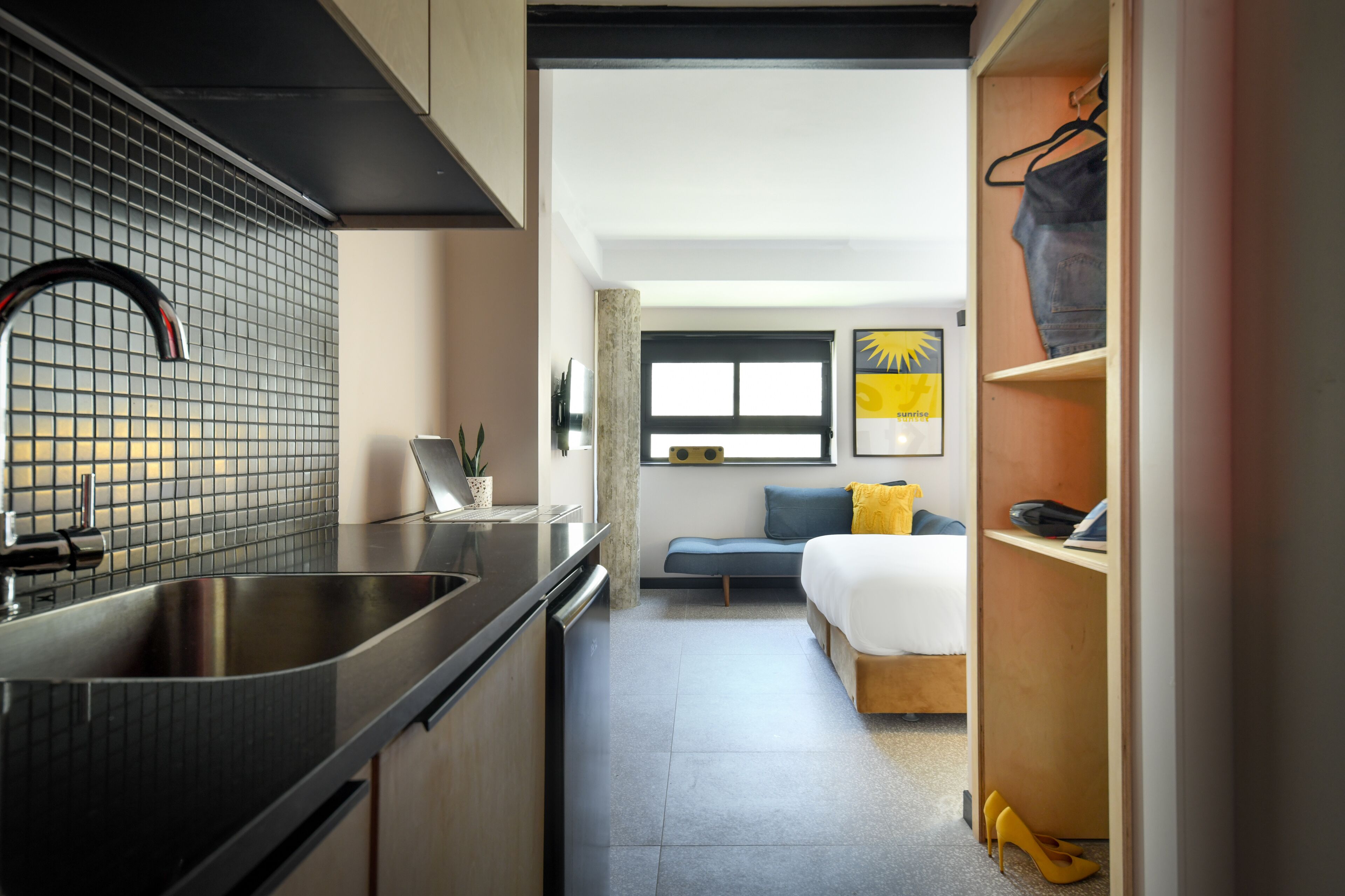 Une chambre d’hôtel compacte comprenant un coin cuisine, un lit, un espace salon et une armoire.
