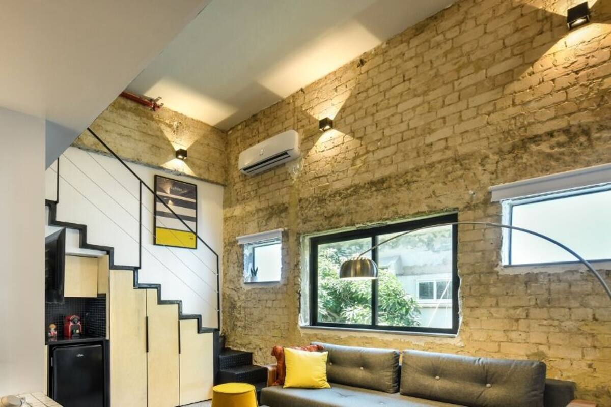 A modern living room with a staircase, a sofa, and a large framed artwork.