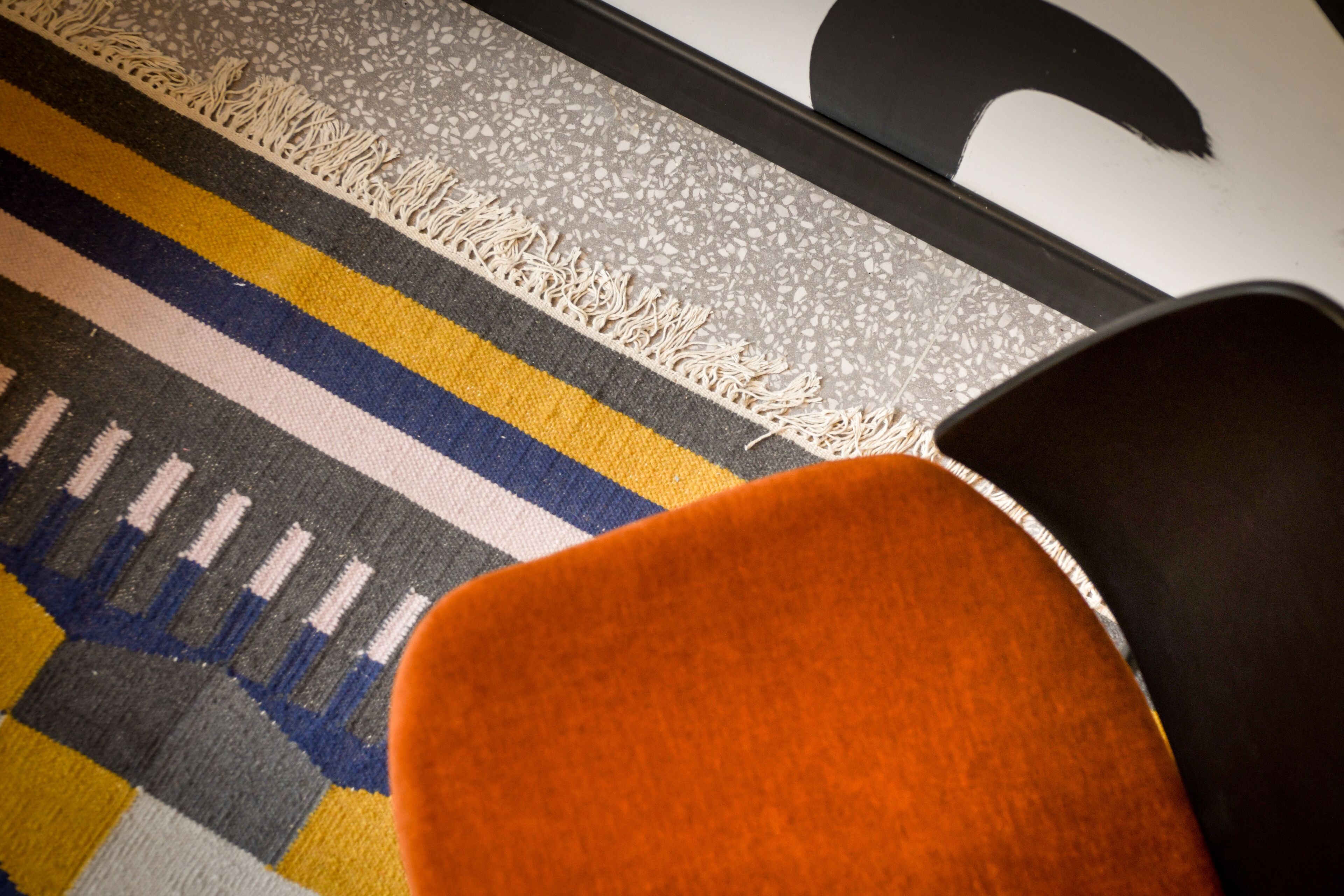A close-up of a patterned rug with a chair partially visible.