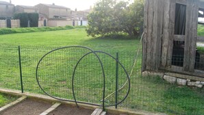 A fenced garden area with raised beds, a wooden structure, and a residential background.