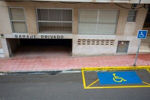 A building entrance labeled 'GARANZE PRIVADO' with a wheelchair-accessible parking space marked with a blue sign and yellow lines. - Fidalsa Feel the Sea (Guardamar)