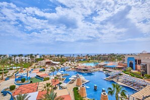 A resort with multiple swimming pools, sun loungers, and palm trees.