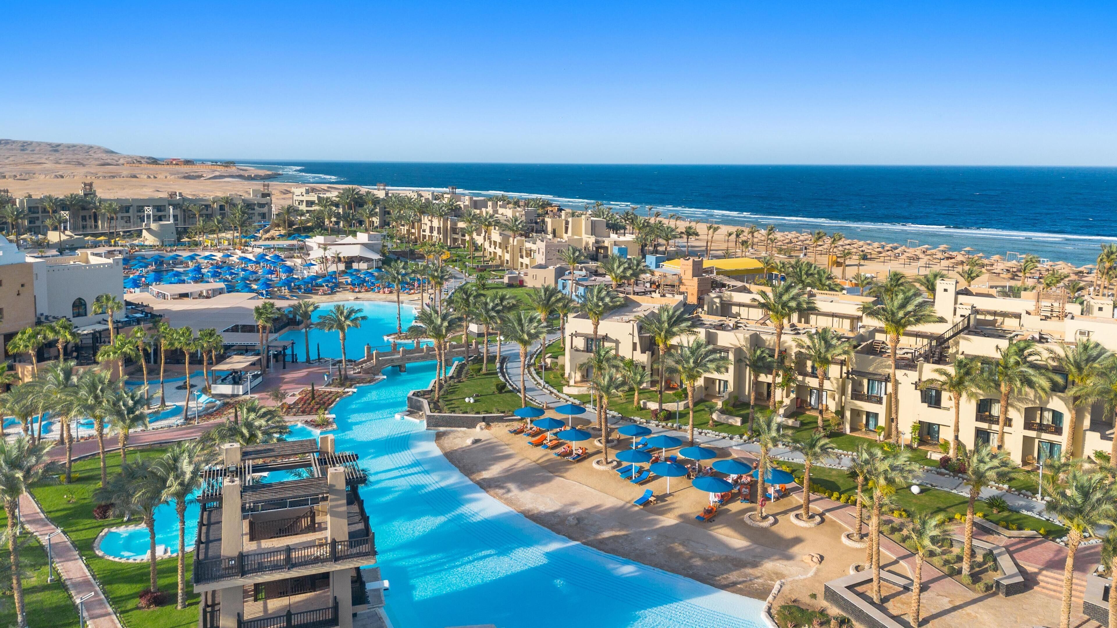 A resort with a central swimming pool, multiple guest buildings, and a beach area.