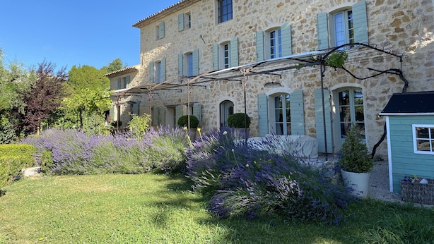Un edificio de piedra con varias ventanas y un jardín de plantas de lavanda.