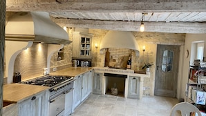 Una cocina rústica con pared de piedra, armarios de madera y un horno de ladrillo empotrado.