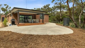 A modern house with a covered patio, a barbecue, and a large window overlooking the yard. - Chatley's (Aireys Inlet)