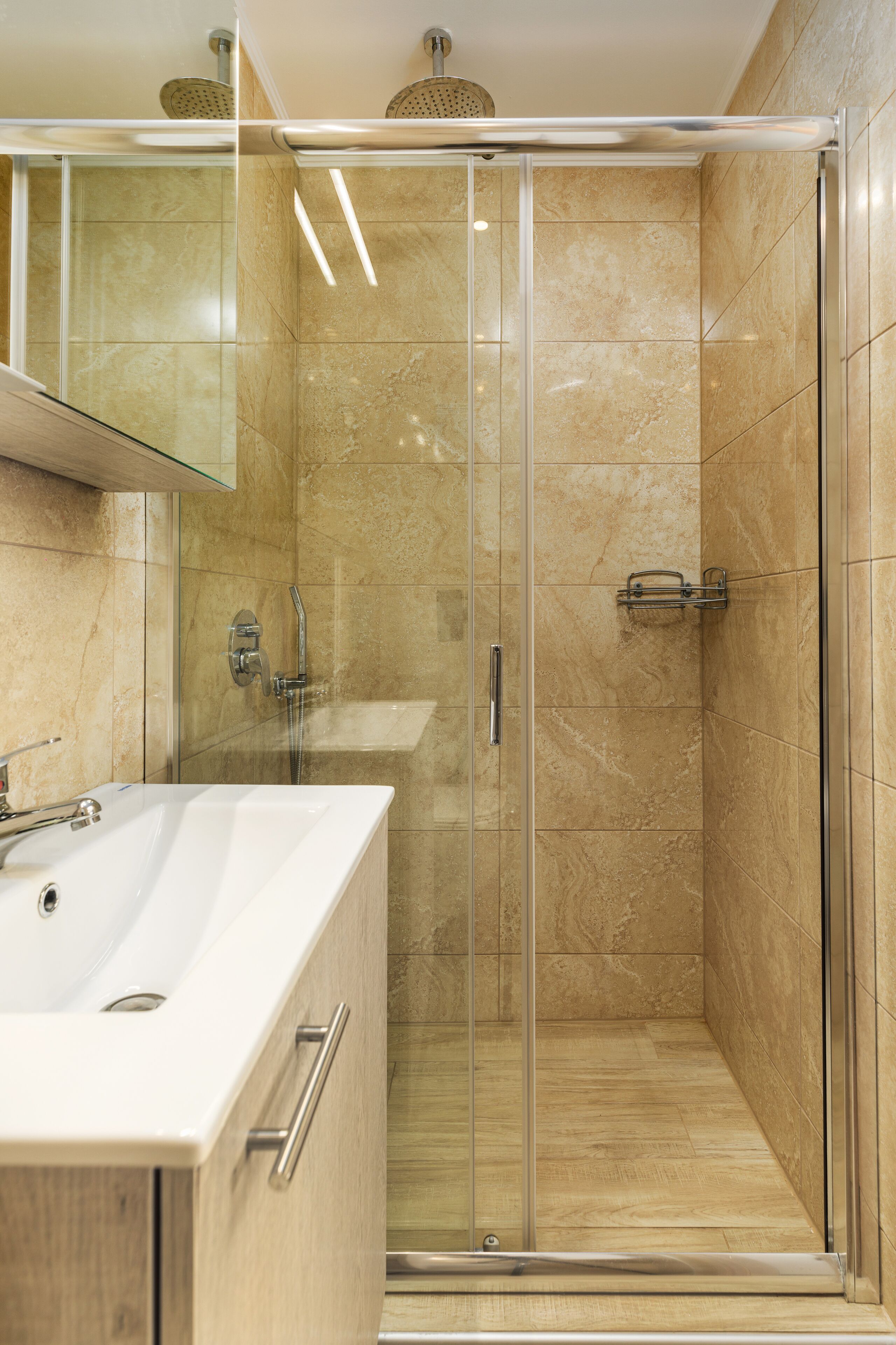 A modern bathroom with a glass-enclosed shower, a white sink, and a mirror above it.