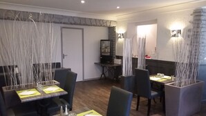 Un comedor con mesas y sillas, una pared de acento de piedra y una puerta.