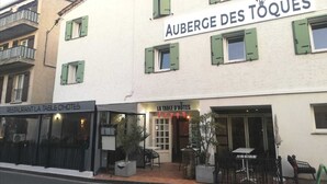 Un edificio con un cartel que dice "AUBERGE DES TOQUÉS" y un restaurante llamado "LA TABLE D'HOTES" debajo.