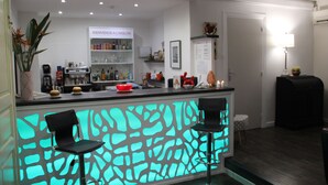 Una cocina moderna con barra, que incluye un mostrador iluminado con neón, dos taburetes de bar y una variedad de electrodomésticos y adornos de cocina.