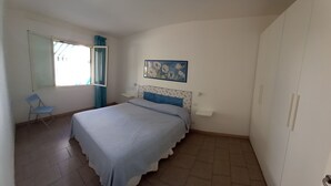 Une chambre à coucher avec un lit, une chaise, une fenêtre et un tableau accroché au mur.