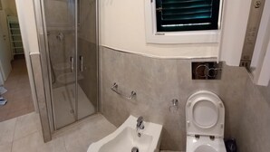 Une salle de bain avec une douche à parois de verre, un lavabo et des toilettes.
