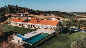 Una amplia villa con piscina, zona de estar exterior y tejado de tejas rojas.