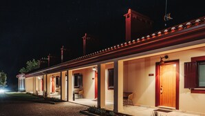 Un hotel con un área exterior cubierta, habitaciones separadas con puertas y una entrada pavimentada.