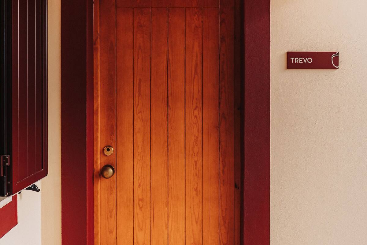 A wooden door with a brass doorknob and a nameplate reading "TREVO".