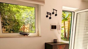 A living room with a patterned sofa, a wooden cabinet, and a large window with a view of greenery.