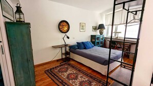 A bedroom with a bed, a desk, a chair, a lamp, a rug, and a decorative lantern.