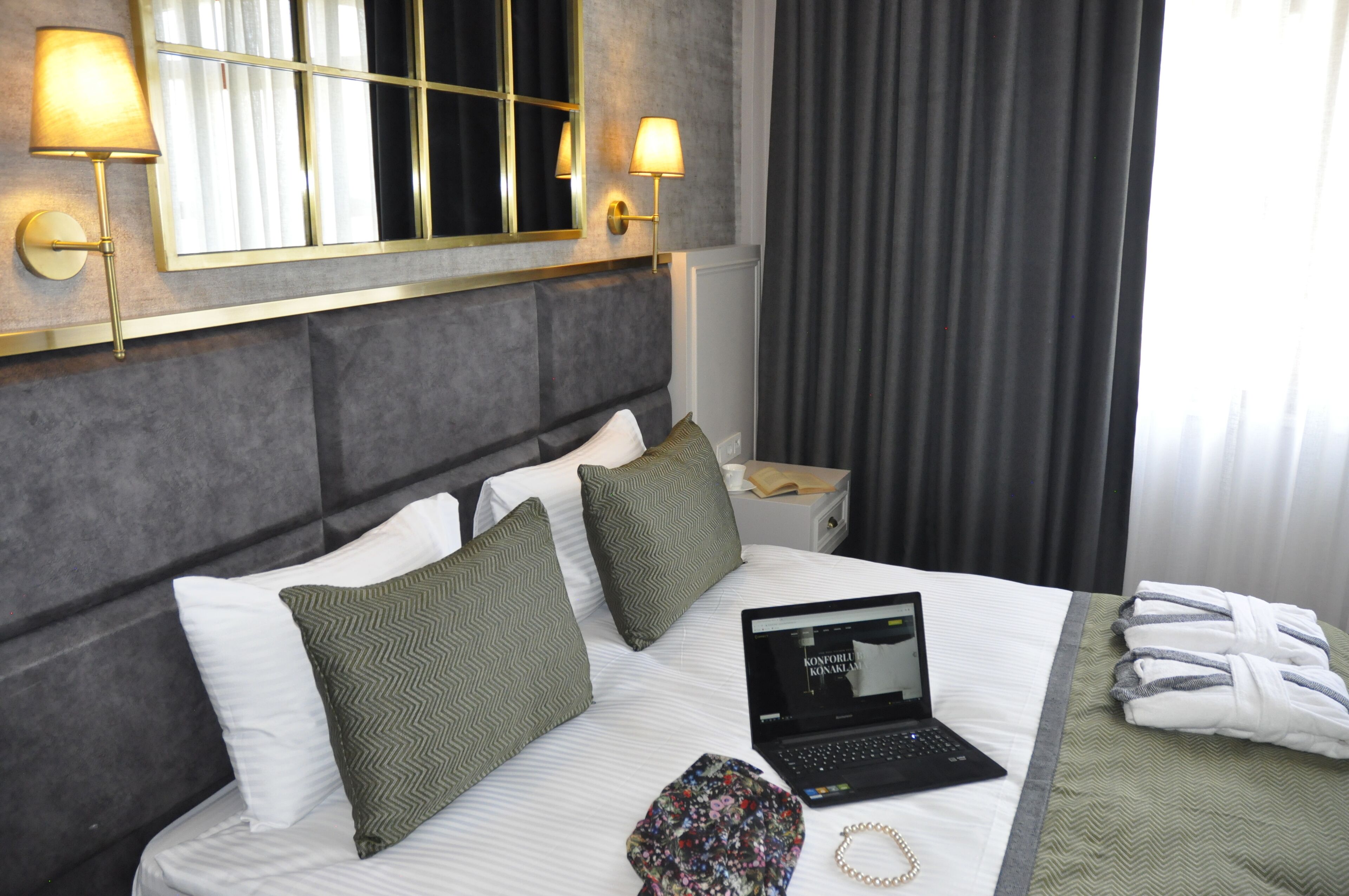 Une chambre d  ’hôtel avec un lit, des oreillers, un ordinateur portable, un peignoir et des serviettes.