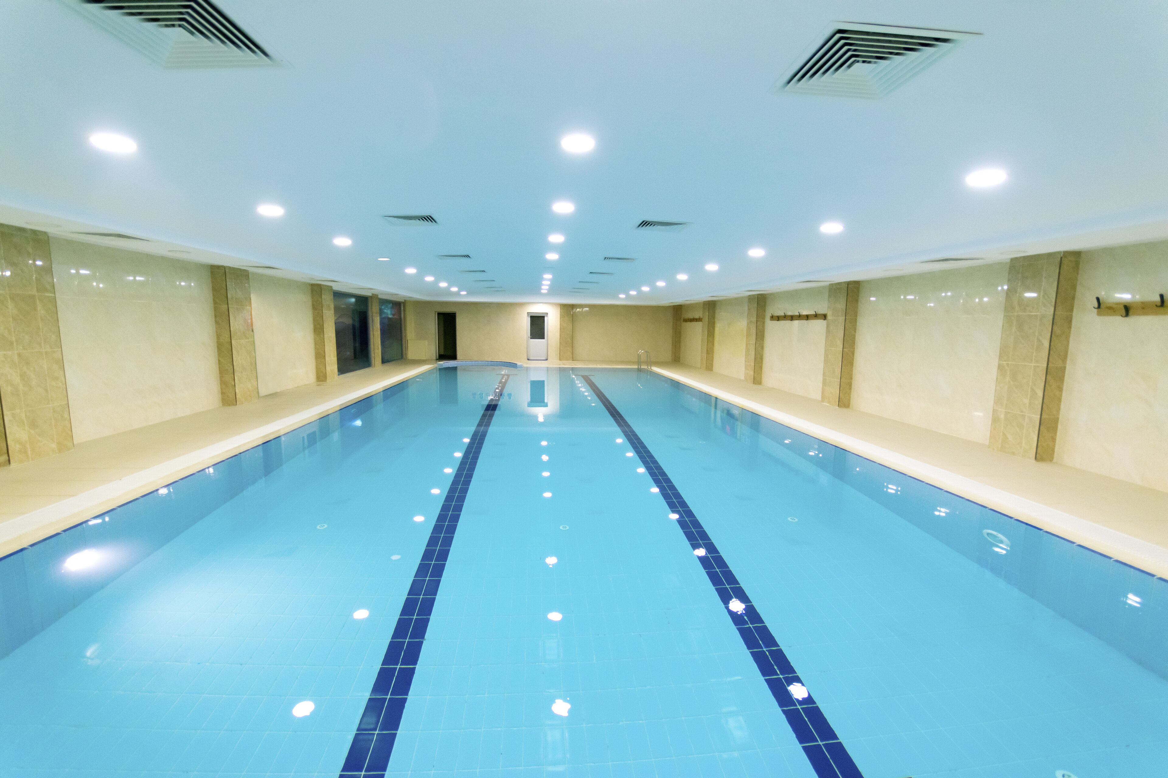 Una piscina coberta llarga i estreta amb rajoles blaves i un separador central de carrils.