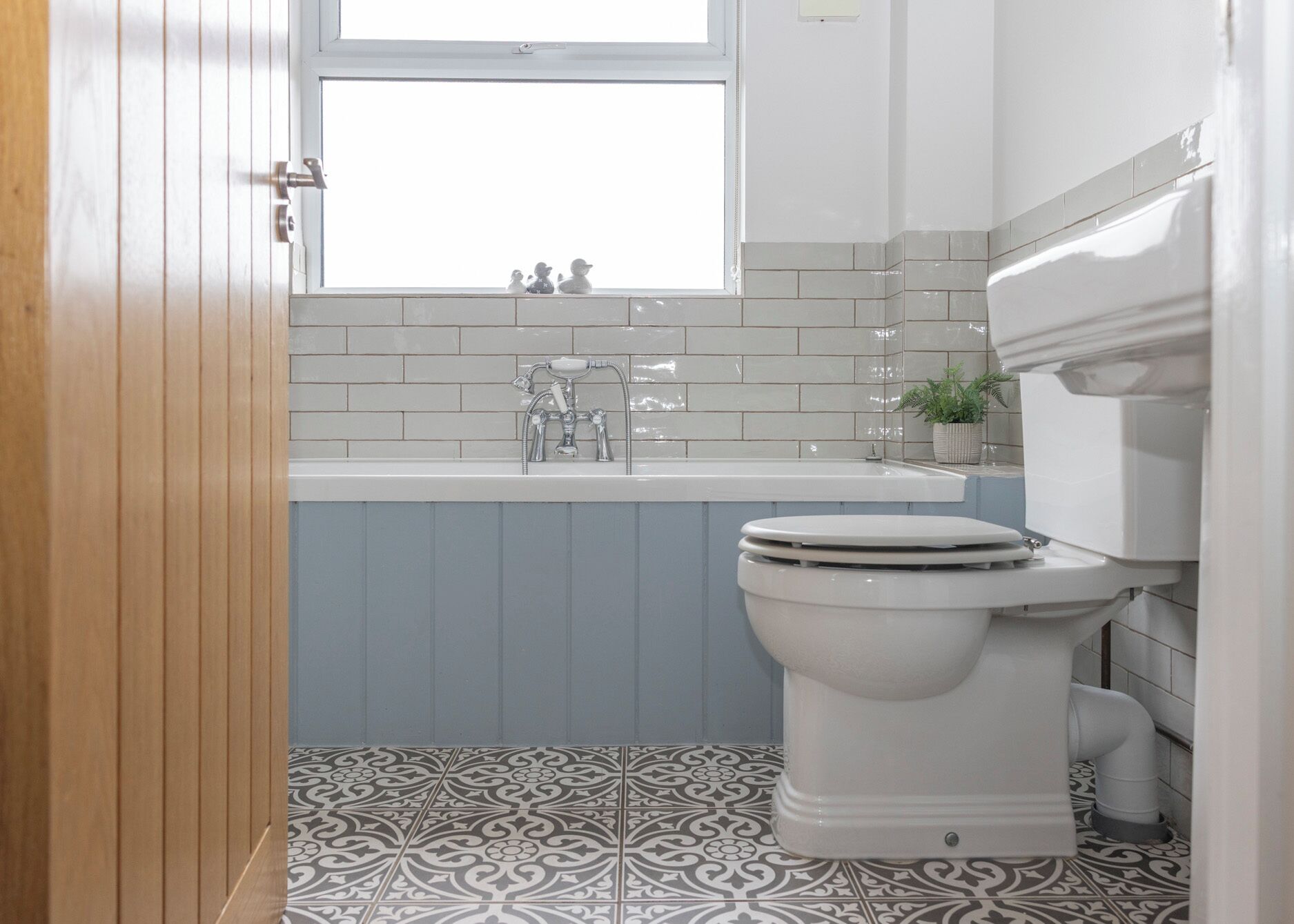A bathroom with a white toilet, a sink with a mirror, and a window above the sink.