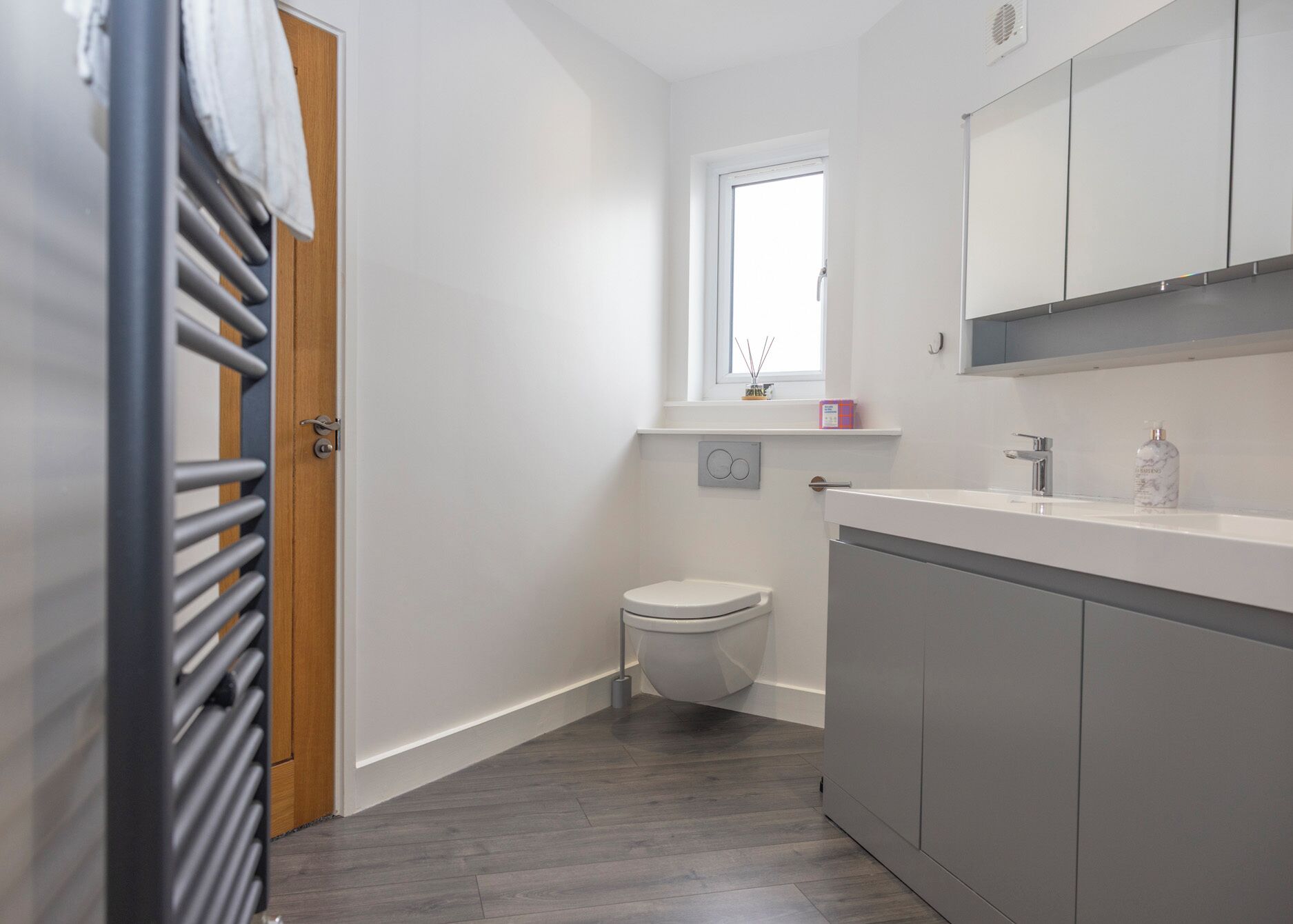 A compact bathroom with a toilet, a window, and a vanity with a mirror.