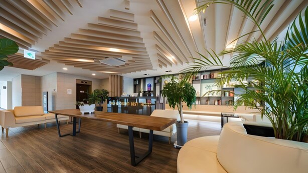 A modern lobby with a wooden floor, a central table, and a seating area with a sofa and chairs. - Chungchoho Best Hotel (Sokcho)