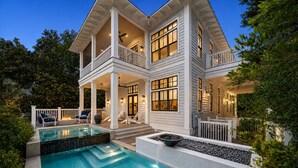 Ein zweistöckiges Haus mit Pool, Gartenmöbeln und einer überdachten Veranda.