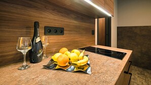 Una cocina con protector de salpicadero de madera, una botella de vino, una copa y un cuenco de frutas sobre la encimera.