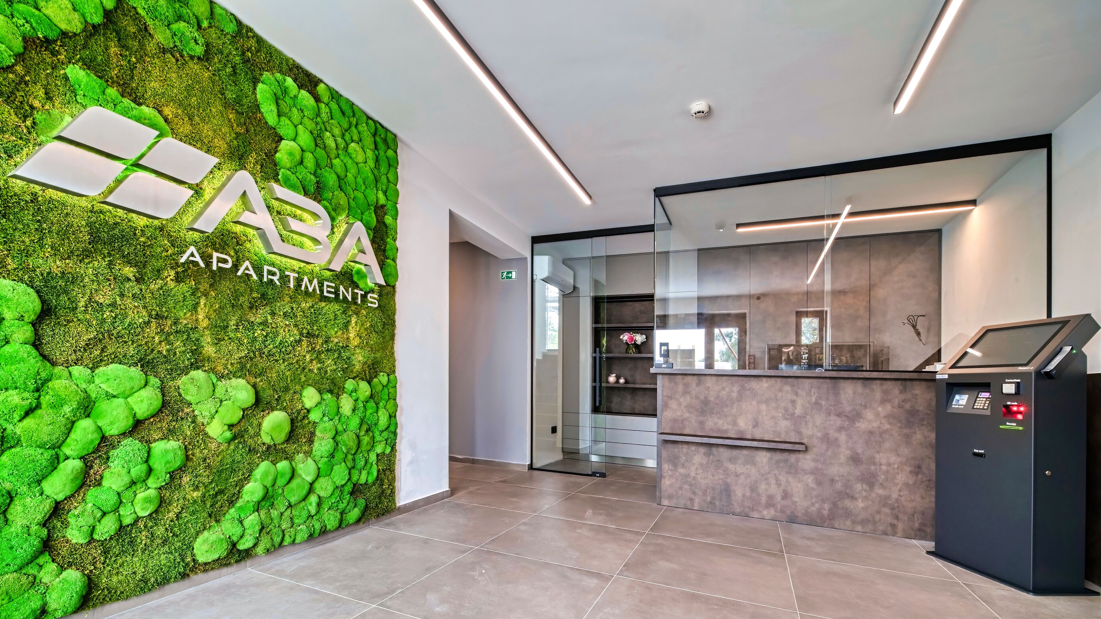 A reception area with a green moss wall, a reception desk, and a modern interior design.