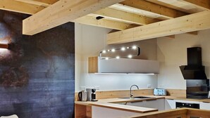 Una cucina moderna con travi in legno, un bollitore in acciaio inossidabile, un tostapane e un forno integrato.