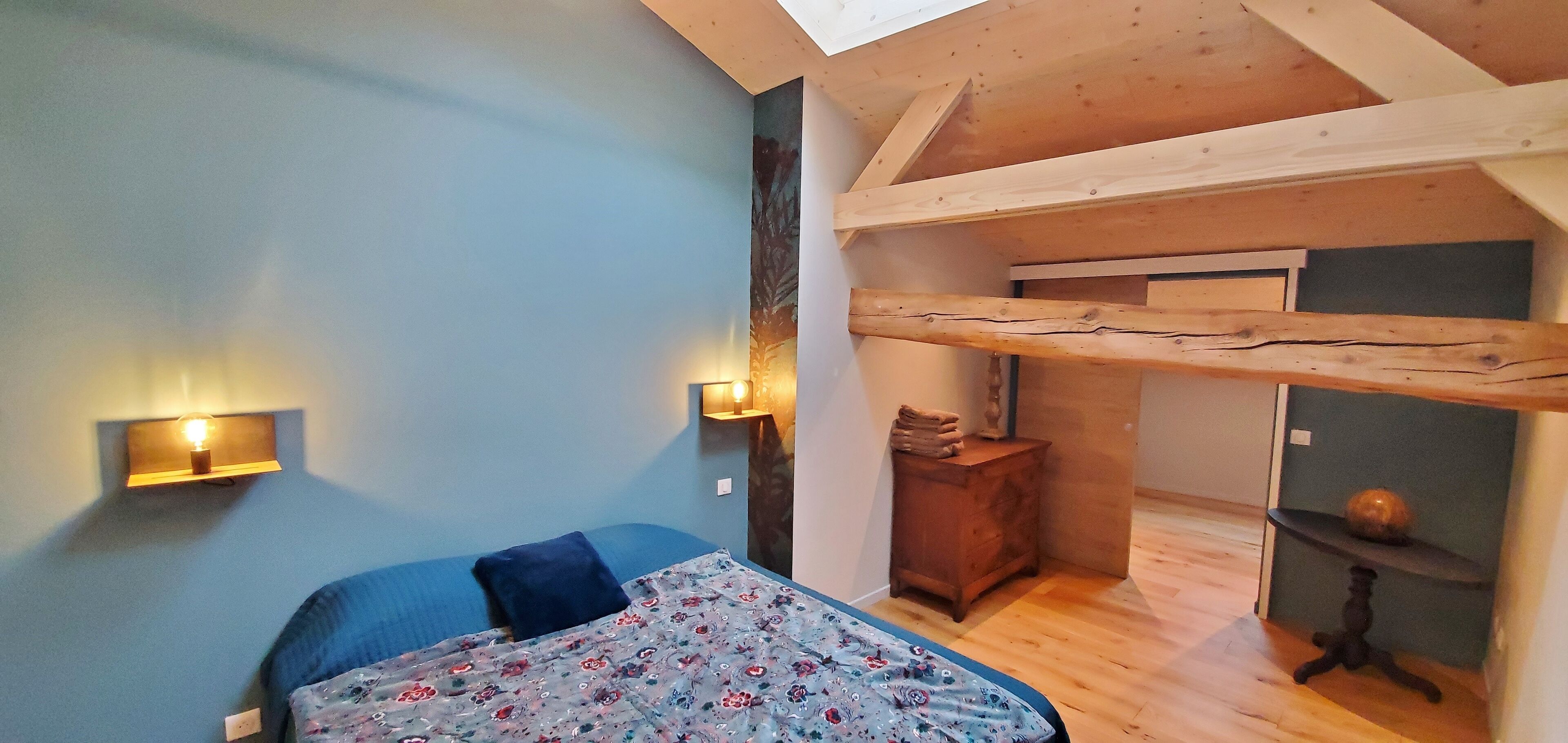 A bedroom with a bed, a wooden dresser, and a small table with a lamp.