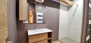 A modern bathroom with a wooden vanity, a white sink, and a mirror above it. - Large new 150 m² Triplex in the heart of Embrun. Mountains with space! (Embrun)