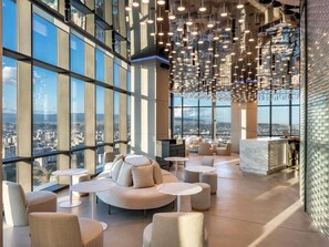 A modern lounge with a city view, featuring round tables, sofas, and hanging lights. - Pullman Tbilisi Axis Towers (Tbilisi)