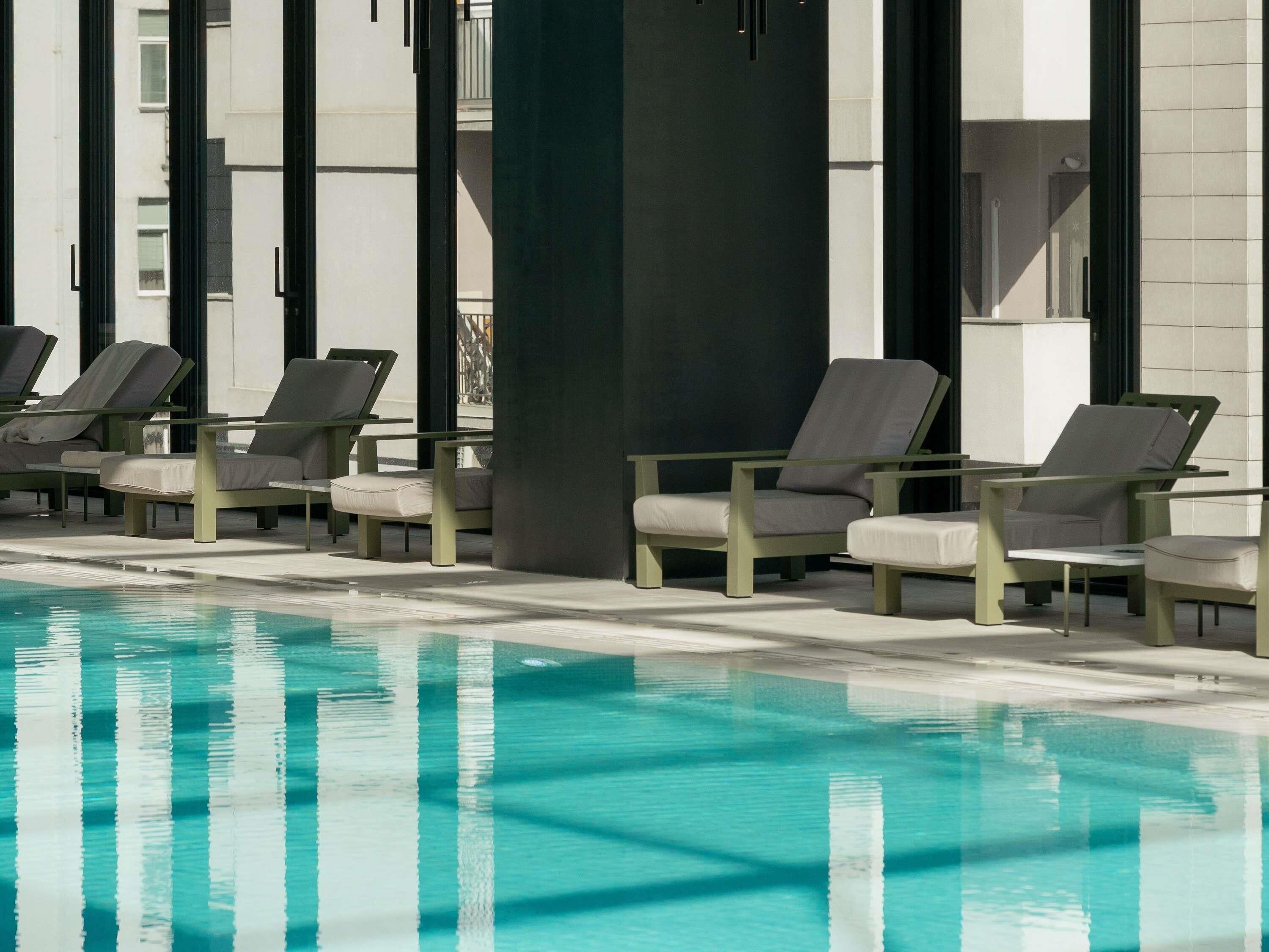 Zona de piscina con sillones de descanso y una piscina.