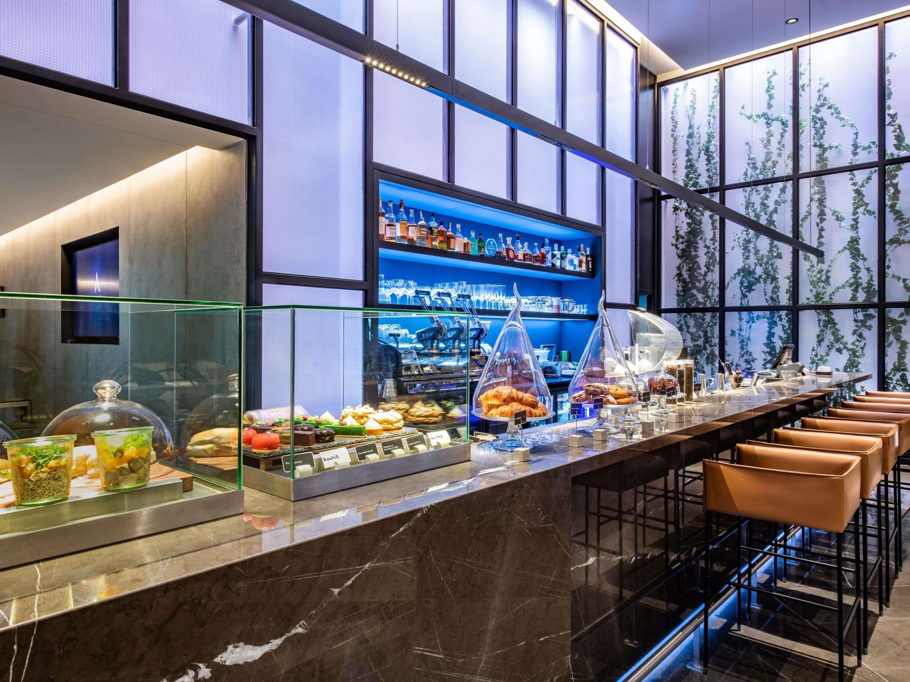 A bar area with a marble countertop, glass display cases, and a variety of food items.