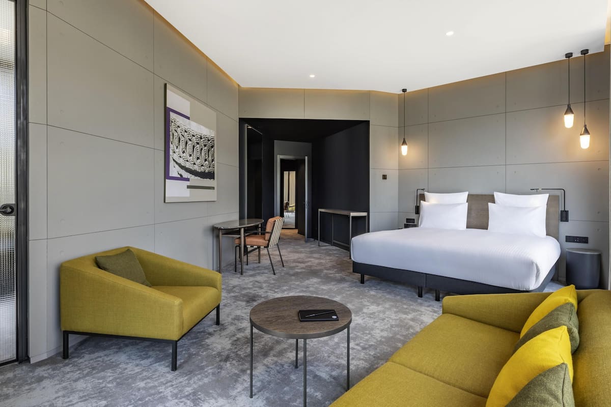 A modern hotel room with a bed, a sofa, a small table, and a chair.