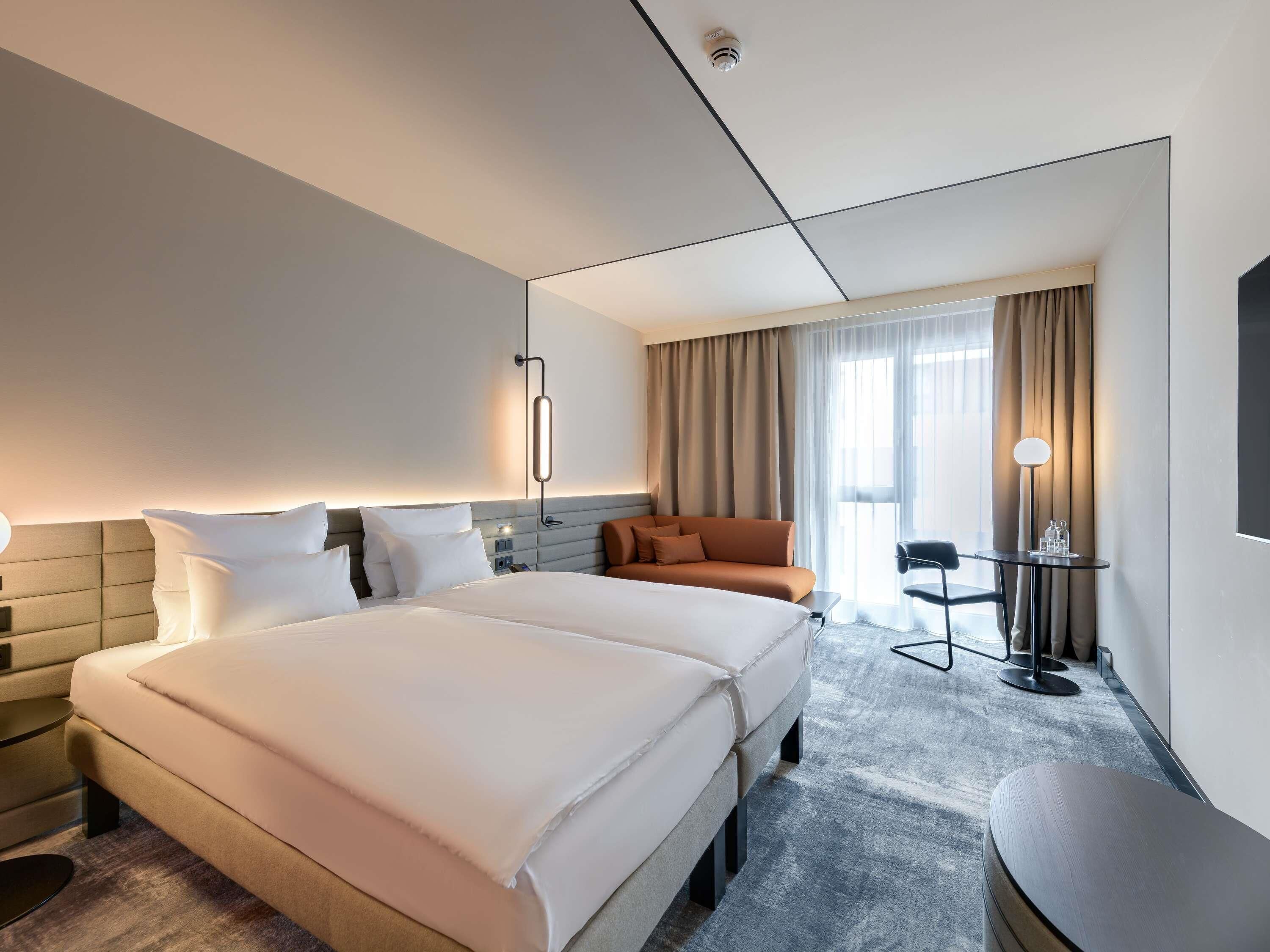 A hotel room with a large bed, a sofa, a desk, and a chair.