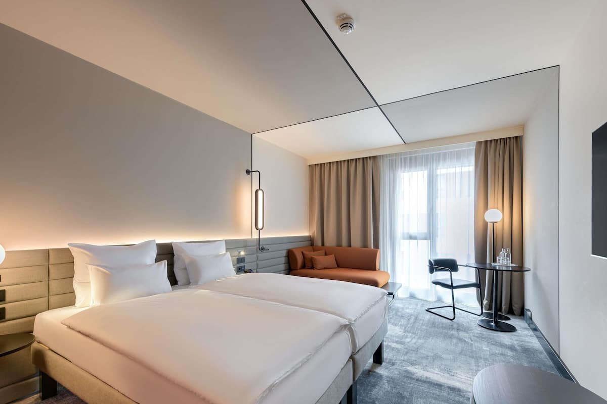 A hotel room with a large bed, a sofa, a desk, and a chair.