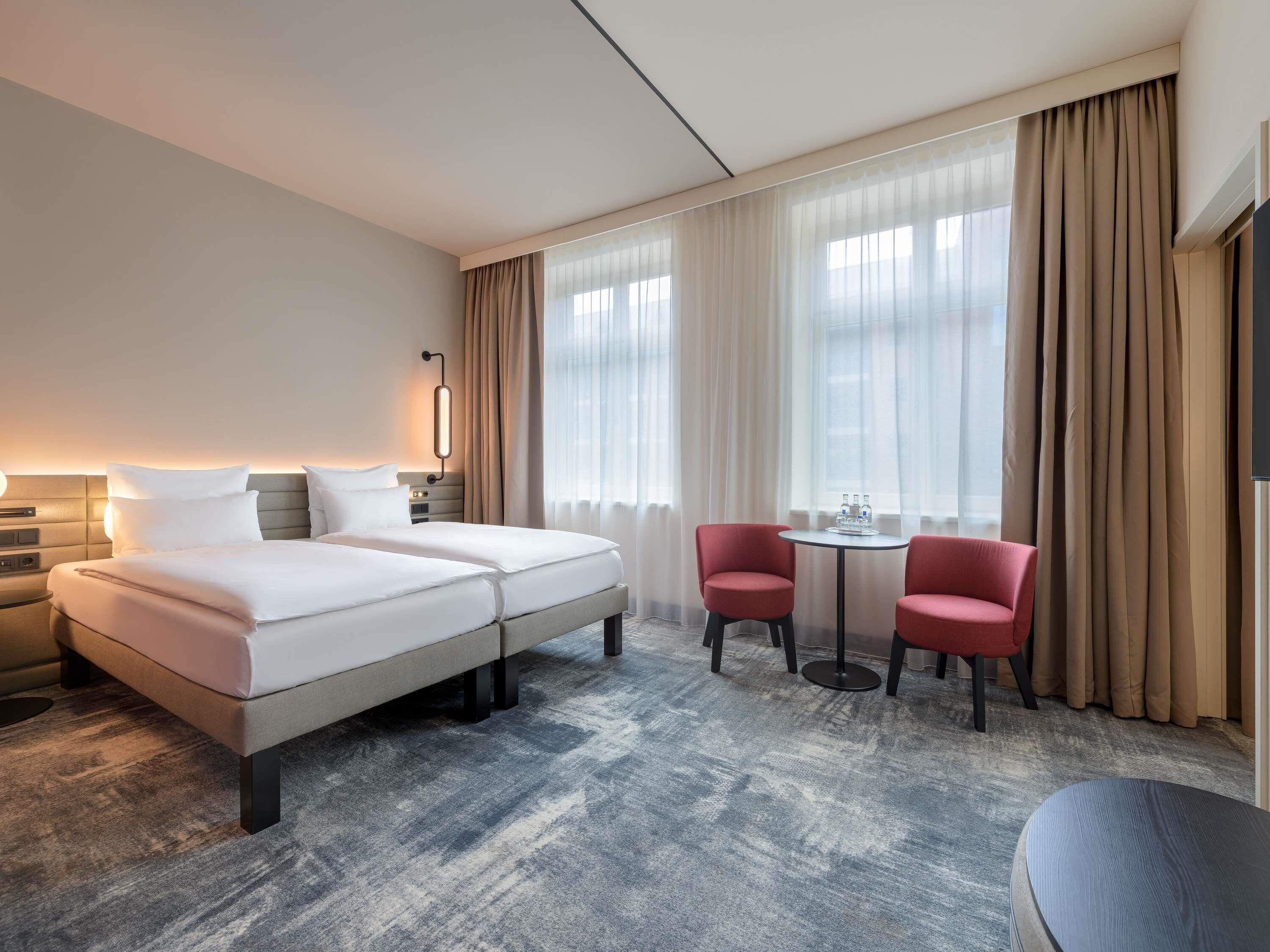 Ein Hotelzimmer mit einem Bett, zwei Stühlen, einem kleinen Tisch und einem Fernseher.