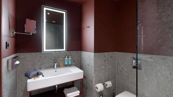 Un baño moderno con lavamanos, espejo y retrete blancos.