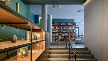 Ein modernes Interieur mit Treppe, Bücherregal und einer Holzablage mit Büchern und einer Glasvase.
