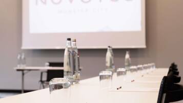 A conference table with water bottles, a pen, and a projector screen displaying 'NOVOTEL'.
