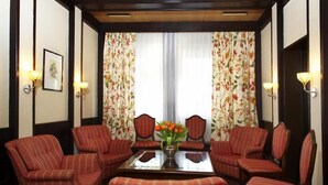 A room with a central table, four striped armchairs, and two lamps. - Stern Hotel Soller (Ismaning)