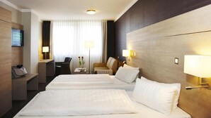 A hotel room with two beds, a desk, a chair, and a TV. - Stern Hotel Soller (Ismaning)