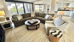 Ein Wohnzimmer mit Sofa, Sessel, Couchtisch und Blick ins Freie.