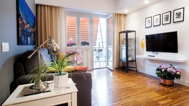 A modern living room with a sofa, a coffee table, a lamp, and a TV. There is a window with curtains and a view of the outside. - Roma-INCANTATA, Large balcony, Central, Next to the main Subway, Lively District (Roma)