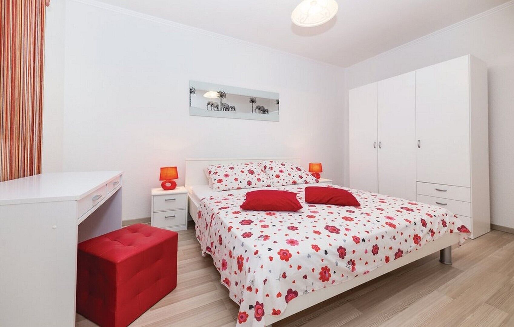 A bedroom with a bed, a desk, a wardrobe, and a nightstand with lamps.