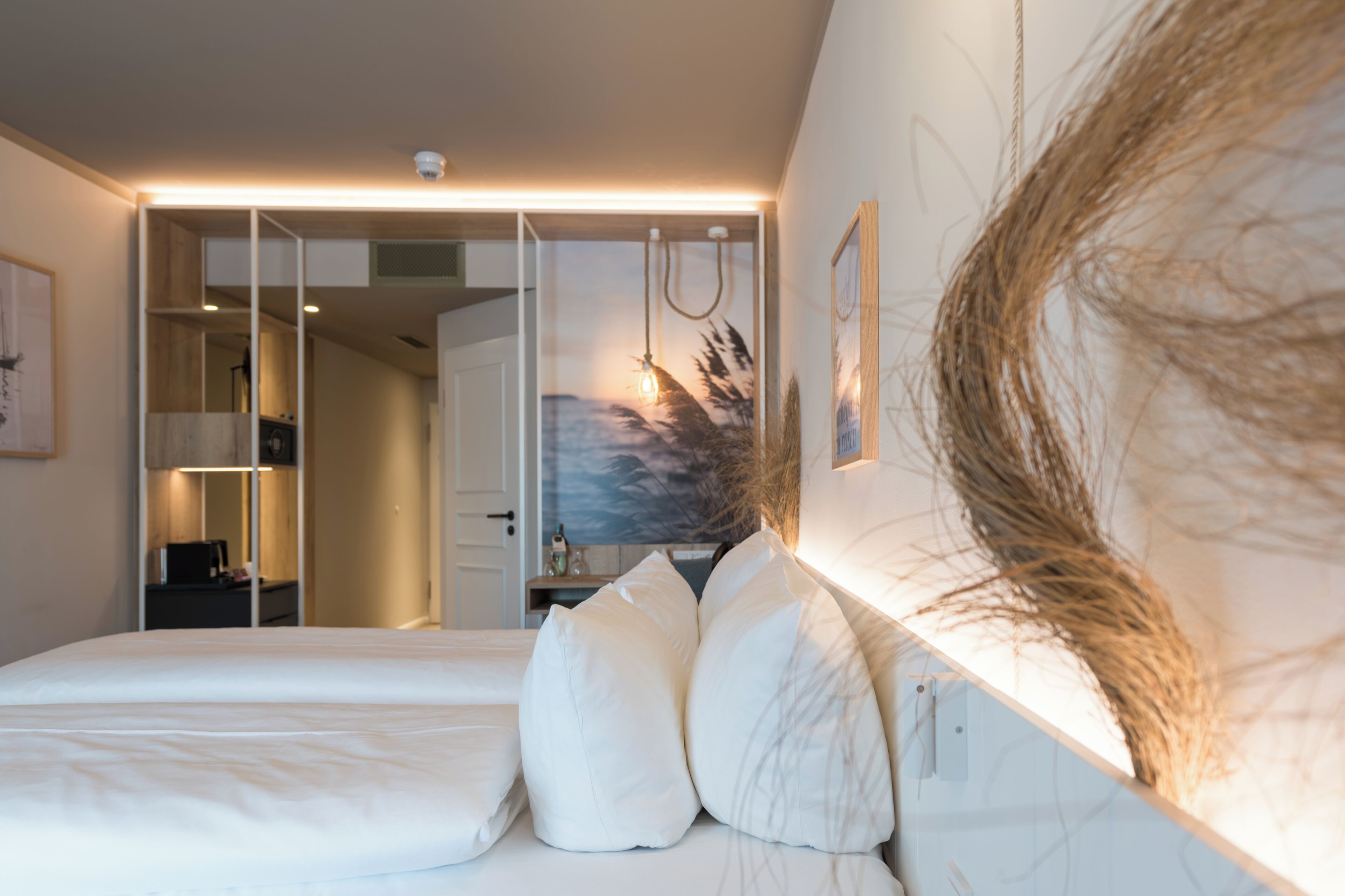 A bedroom with a bed, pillows, a nightstand, a desk, and a painting on the wall.