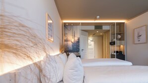 A modern bedroom with a large bed, a wardrobe, and a mirror. - Hafenhotel zu Putbus (Putbus)