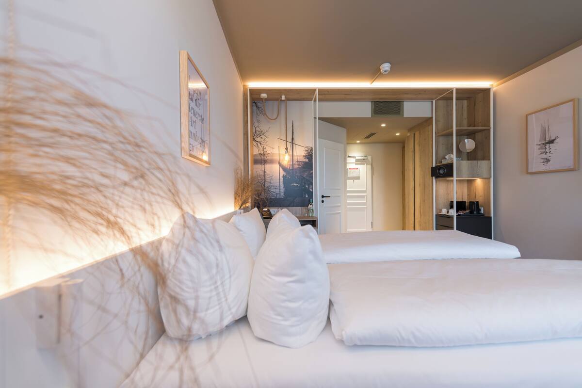 A modern bedroom with a large bed, a wardrobe, and a mirror.